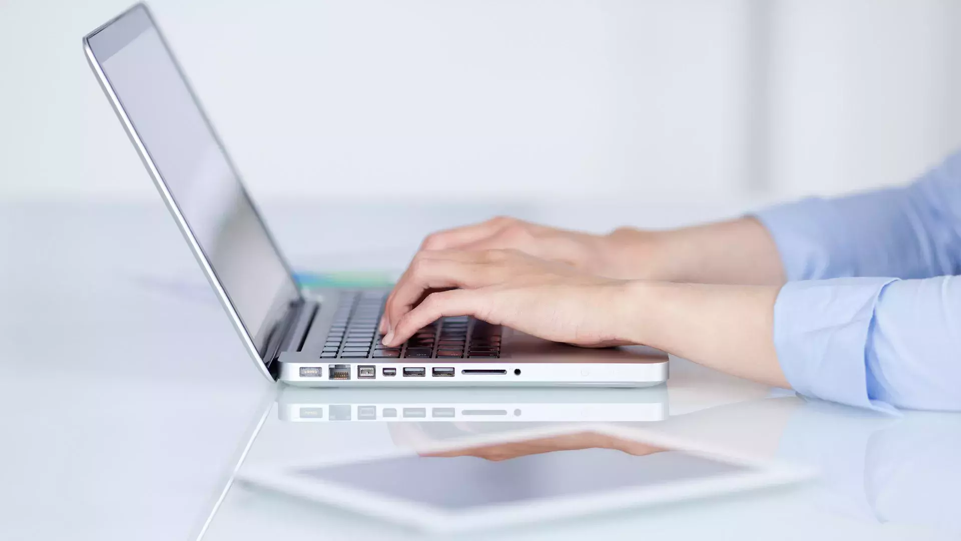 mani che scrivono su laptop