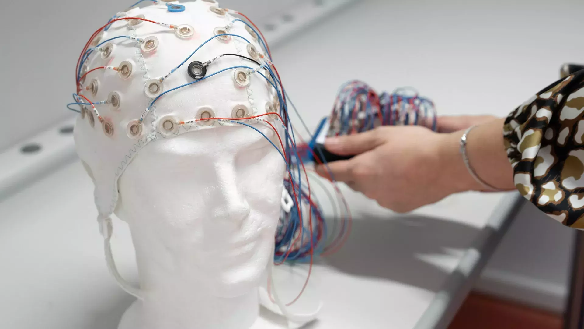 particolare cuffia EEG e mani ricercatrice