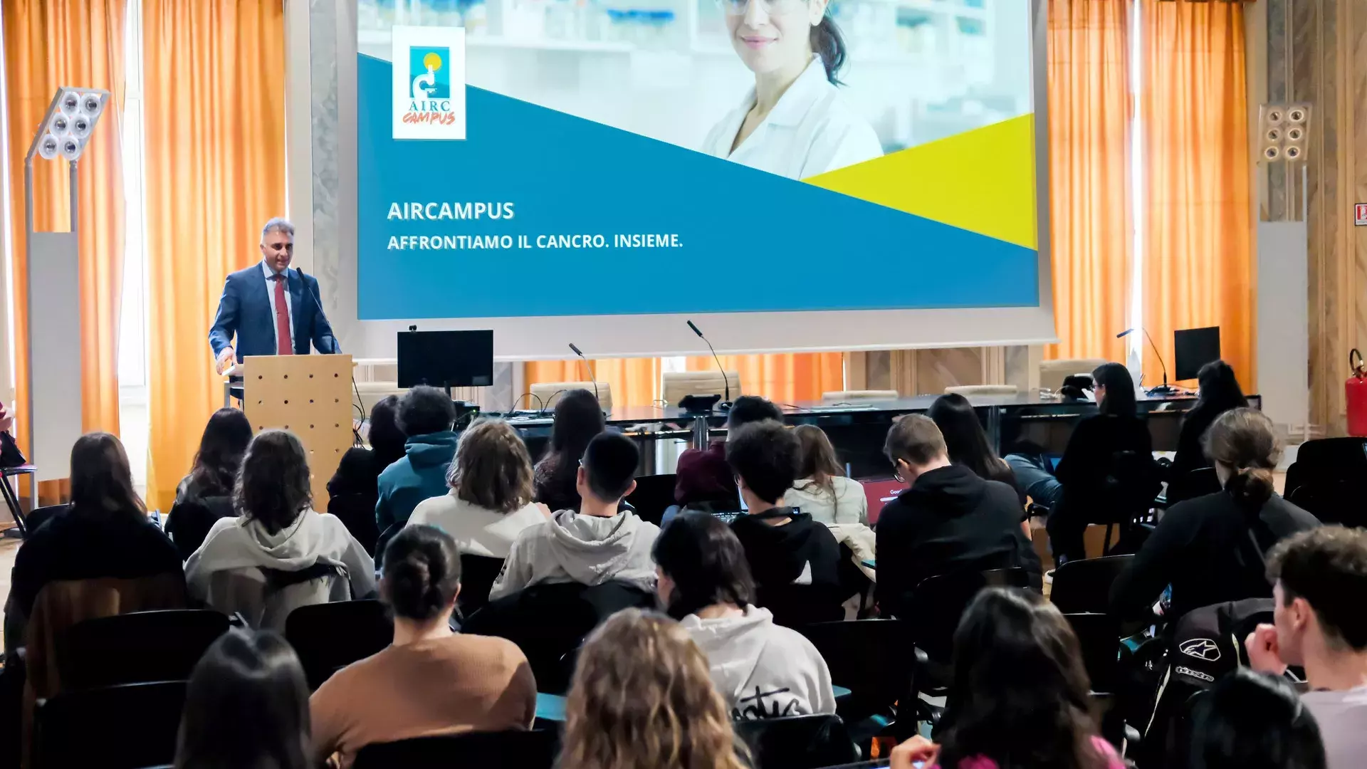 aula con persone di schiena, evento AIRC