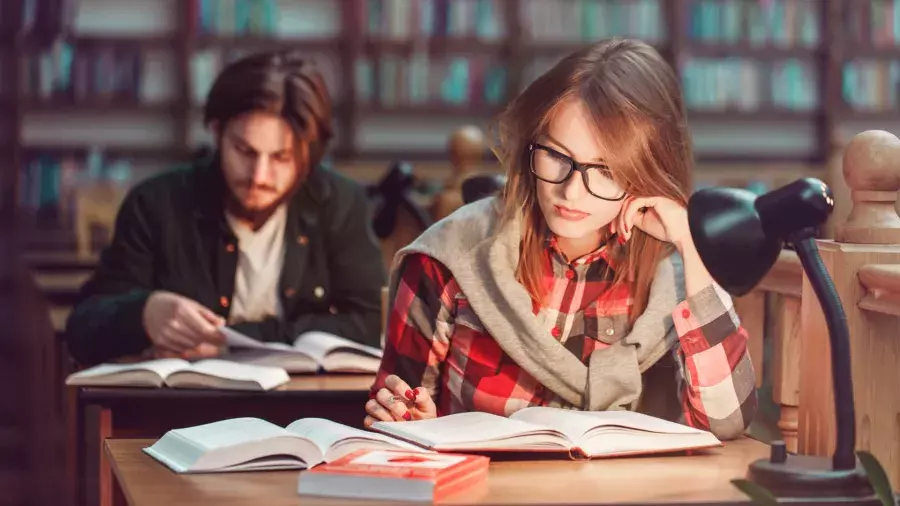 Ragazza e ragazzo che studiano in biblioteca