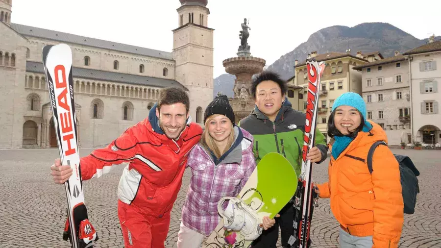 Ragazzi e ragazzi in Piazza Duomo con tute e sci e snowboard