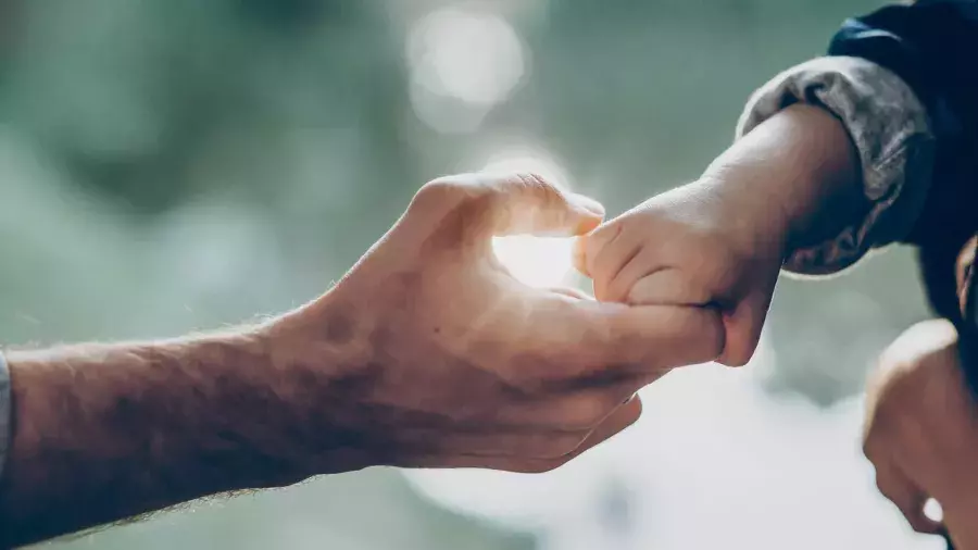 Mano di bambino che tiene il dito di mano adulta