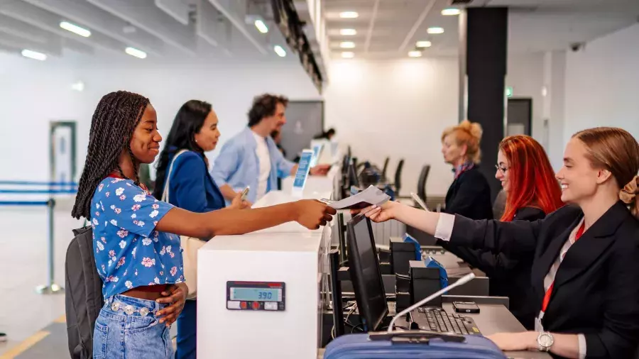 Ragazza di colore vestita di blu che consegna il suo biglietto al check in in aeroporto